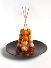 Standing spicy skewered meatballs on the brown plate