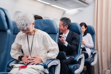 飛行機の機内で体調不良に苦しむ高齢の女性 - obrazy, fototapety, plakaty