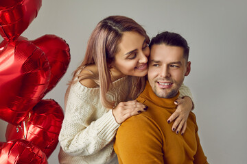 Romantic couple. Portrait of tender young couple in love posing near red heart-shaped balloons...