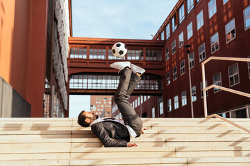 Image of a businessman and soccer freestyle player making tricks with the ball on the street. Concept about sport and business people	