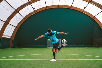 Cinematic image of a soccer freestyle player making tricks with the ball on a artificial grass...