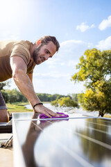 Man cleaning the solar panel on the roof of a camper van with a cloth