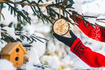 Feeding birds in winter. Woman with bird food. Bird feeders.