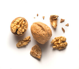 whole walnut plus open walnut with scattered shell parts on white background
