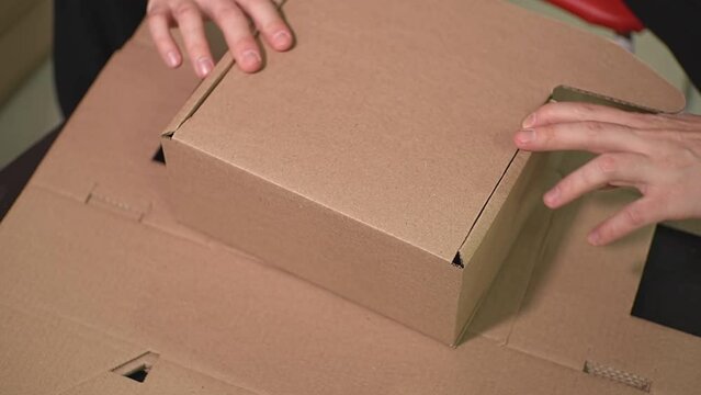 the man himself folds the brown cardboard box according to the brochure. view from above. High-quality Full HD video recording. live video