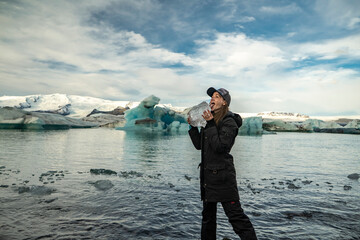 young girl woman licks ice at Jökulsárlón glacier at the beach