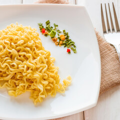 Ramen on a white plate with dry vegetables