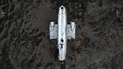 aerial view of young woman laying at damaged dc 3 plane in iceland black beach