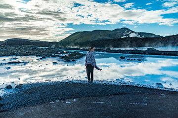 young woman at blue lagoon with blue water and reflections of sky and rocks