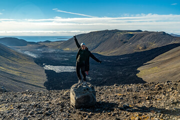 young woman poses for camera on the rock at Fagradalsfjall volcano valley in iceland - obrazy, fototapety, plakaty