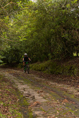 Obraz premium Unrecognizable cyclist woman, wearing glasses and helmet, riding her bike while descending a mountain on a stone path