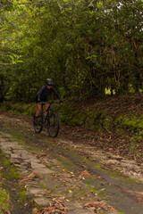 Fototapeta premium Sporty woman riding her bike while descending the mountain on a stone path