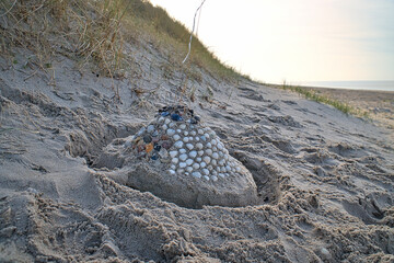 Sand castle with shells and sand. Moat around the castle in front of dunes. Denmark