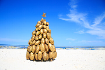 Fototapeta na wymiar A golden christmas tree made of coconuts on the white beaches of Zanzibar