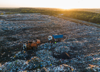 Garbage truck unloads rubbish in landfill. Landfill waste disposal. Garbage dump with waste plastic...