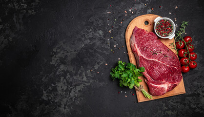 Fresh and raw beef meat. Whole piece of tenderloin with steaks and spices ready to cook on dark background, banner, menu, recipe place for text, top view