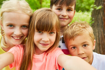 Group of children taking selfie photo with smartphone in nature