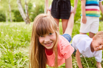 Girl playing with friends during wheelbarrow race competition