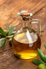 Olive oil in bottles with black and green olives and leaves. extra virgin olive oil jars on a wooden background. vertical image. top view. place for text