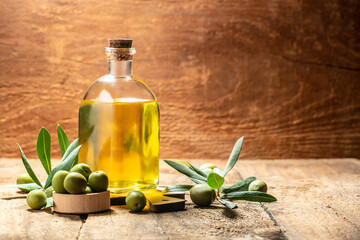 olives berries in wood bowls and oil in glass bottles on a wooden background. Healthy and detox...