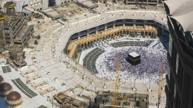 Time lapse of Muslim pilgrims circling around the holy Kaaba at noon and praying inside al Masjid al Haram in Mecca, Saudi Arabia.  Zoom out motion timelapse. Prores UHD