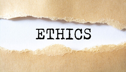 Ethics word written under torn white paper. Business social concept.