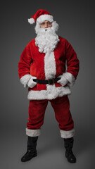 Studio shot of cheerful elderly santa dressed in red winter costume.