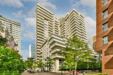 some tall buildings in the middle of an urban area with green trees and people walking on the...