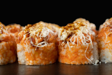 Hot sushi roll with cheese top. Baked sushi with seafood and crab, cream cheese topped on black background.