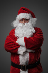 Portrait of isolated on grey santa dressed in red costume staring at camera.
