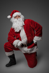 Shot of santa claus with winter hat and clothes looking at camera while sitting.