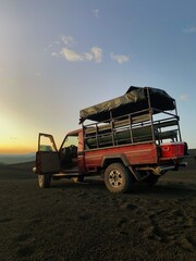 Pickup truck on dark black volcanic gravel during sunset. Pickup truck sunset scene. Sunset drinks....