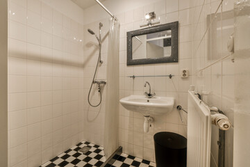 Flush toilet and shower cabin with tile partition and curtain located near sink and mirror in...