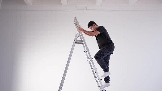 Unlucky male maintenance worker climbs a ladder with a wrench and loses his balance and falls down. Funny fail.
