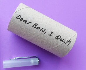 Blur pen on purple background with toilet paper roll written DEAR BOSS I QUIT, concept of employee decides to leave work, quitting full time job after pandemic in the great resignation phenomenon