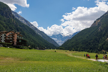 Fototapeta na wymiar Mountain Range of the Italian Alps on a Sunny Summer Day- view of the Green Meadow and Blue Sky