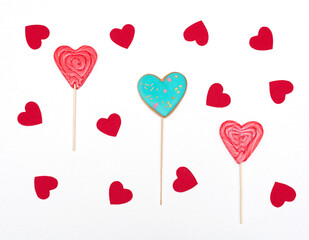 Fototapeta na wymiar Valentines day card with heart shaped gingerbread and lollipops on white background with red hearts. Love, holiday concept. Flat lay style