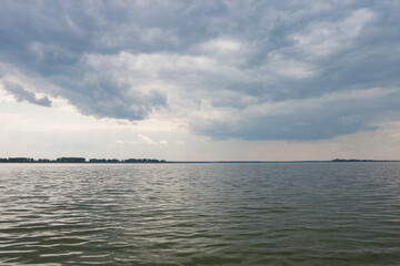 Sunset on the lake. Evening sky with beautiful clouds is reflected in the water of the lake
