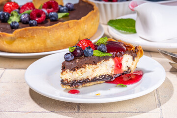 Homemade cheesecake with chocolate and berry. Sweet cottage cheese cake pie with fresh and chocolate topping, classic dessert om beige tiled table copy space