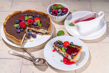 Homemade cheesecake with chocolate and berry. Sweet cottage cheese cake pie with fresh and chocolate topping, classic dessert om beige tiled table copy space