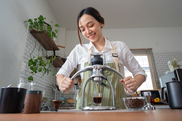 Asian women use a manual process to make espresso with a classic espresso machine at home.