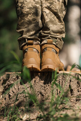 A military man in a special uniform and protective tactical sneakers. Special waterproof sneakers for soldiers in khaki and green