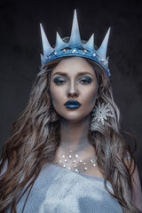 Portrait of winter queen with cloak and curly hairs against dark background.