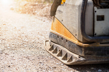 Vibration Plate Compactor heavy Machine  for construction compacting or beating Gravel Sand at sidewalk. Tamping gravel by the Vibration plate Close up. Copy Space