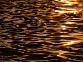 Die Sonne spiegelt sich bei Sonnenuntergang golden auf einer Wasseroberfläche - 554237621