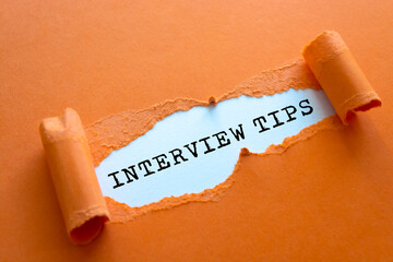 INTERVIEW TIPS words written torn paper.