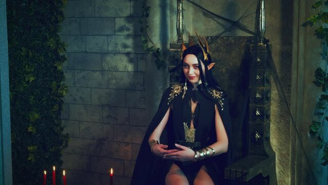 Portrait art fantasy gothic woman queen sits on throne, holds white barn owl on hand. Bird flaps wings flies away. Princess girl sexy vampire, black dress golden crown, old style room. lady goddess