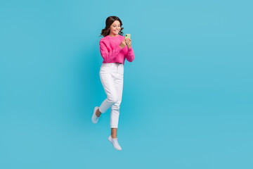 Full length photo of excited cute lady wear pink reading modern gadget empty space jumping high isolated blue color background