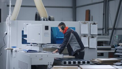 modern furniture factory, milling process in workshop, man is programming woodworking machine