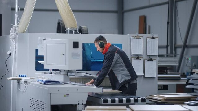 modern furniture factory, milling process in workshop, man is programming woodworking machine